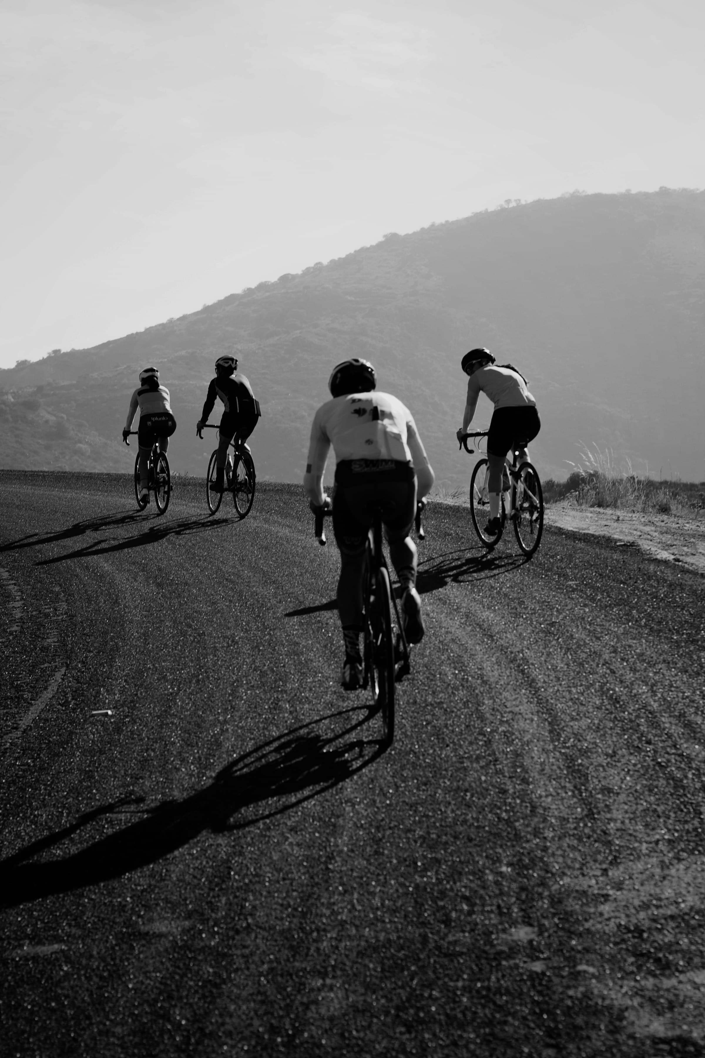 Tres ciclistas subiendo un puerto entre la niebla